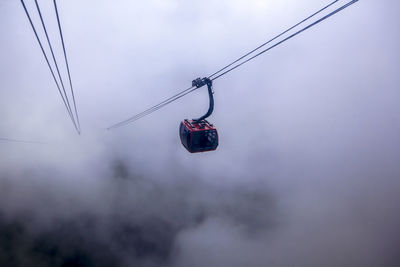 Low angle view of overhead cable cars against sky