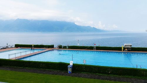 Swimming pool by seaside against sky