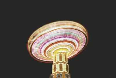 Low angle view of illuminated carousel against clear sky at night