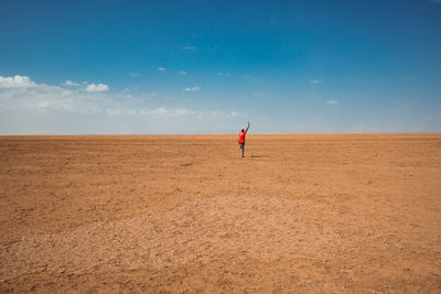 Rear view of a man doing a yoga pose in the desert at chalbi desert in marsabit county, kenya