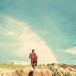 Man standing on rock against sky