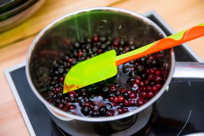 Cranberries are boiled in a saucepan to become jam. acrylic spatula stirs them