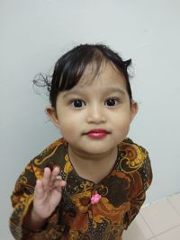 Portrait of cute girl against wall