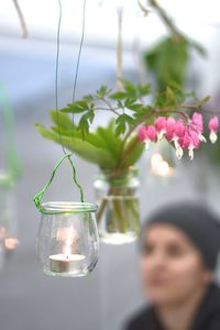 Tea light candle by bleeding hearts hanging in yard with woman in background