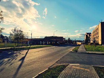 Road by buildings against sky in city