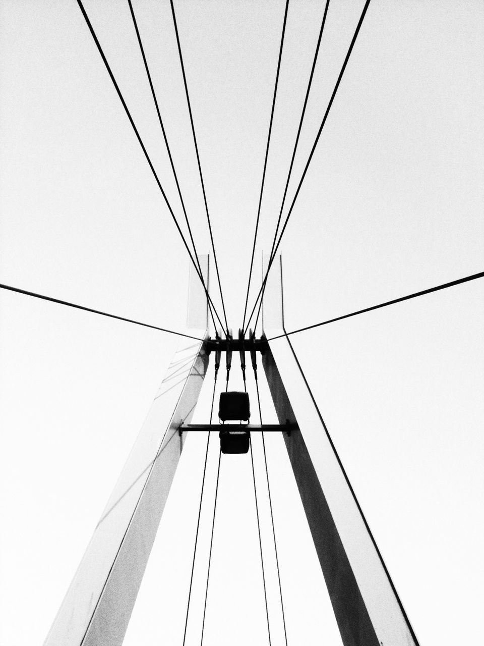 low angle view, connection, power line, cable, clear sky, built structure, architecture, electricity, power supply, electricity pylon, technology, engineering, sky, fuel and power generation, day, copy space, outdoors, diminishing perspective, no people, bridge - man made structure