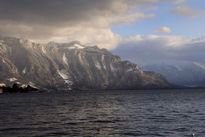 Scenic view of sea and mountains against cloudy sky