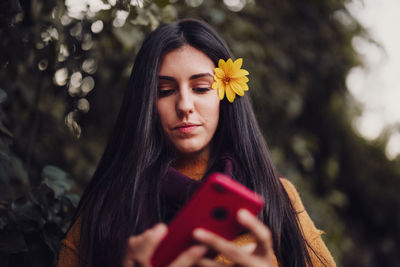 Woman using her phone with flower in her hair