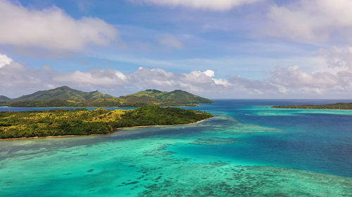 Turquoise ocean waters under the clouds. mountains in the distance. drone view of fiji islands.