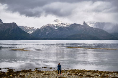 Scenic view of a young girl on a beach in norway during a cloudy day