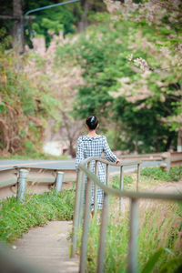 Rear view of woman sitting on railing