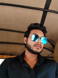 Portrait of young man wearing sunglasses against wall