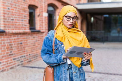 Portrait of young woman standing against wall