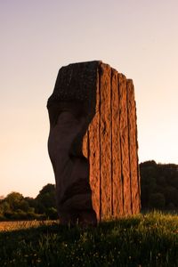 Rock formation on field against clear sky during sunset