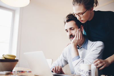Low angle view of couple looking at laptop in domestic room