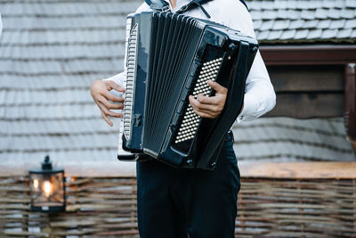 Midsection of man playing accordion while standing outdoors