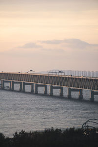 Bridge over sea against sky during sunset