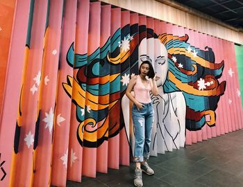 Portrait of young woman standing against graffiti wall