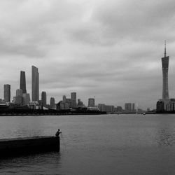 Sea by modern buildings against sky in city