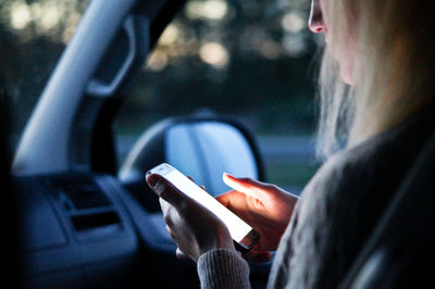 Midsection of man using mobile phone in car