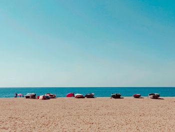 People on beach against clear blue sky