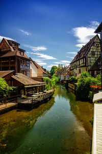 Canal amidst houses and buildings against sky