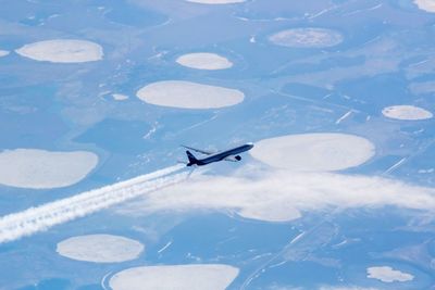 High angle view of airplane flying over lake during winter