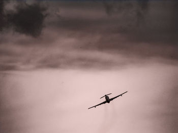 Low angle view of silhouette airplane flying against sky