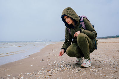 Woman crouching on shore at beach