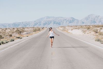 Rear view of woman walking on road in desert