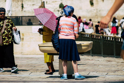 Rear view of people holding umbrella on street