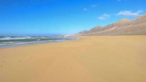 Scenic view of beach against blue sky