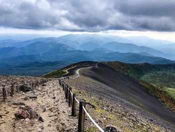 Scenic view of road leading towards mountains against sky