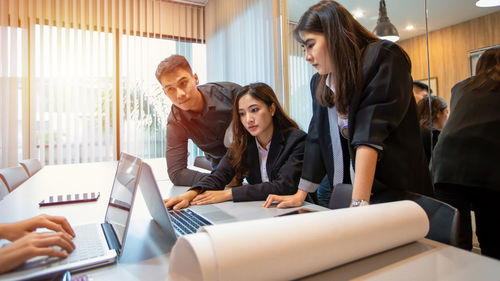 Side view of young woman using laptop at office