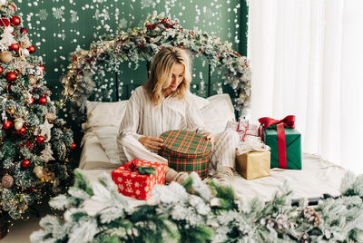 A woman in pajamas opens christmas gifts.