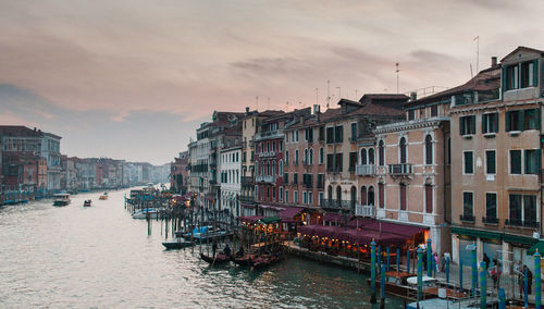 Buildings by sea against sky during sunset