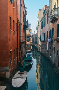 Boats moored in canal amidst buildings in city
