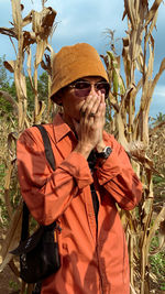 Side view of man wearing hat standing amidst plants on field