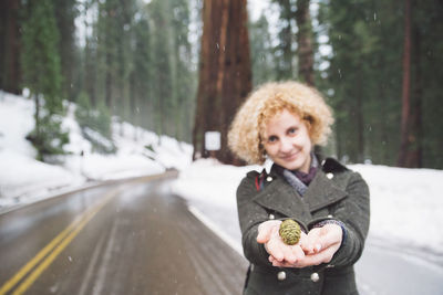 Portrait of smiling young woman holding pine cone