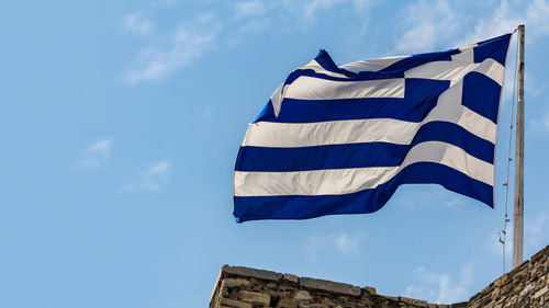 Low angle view of flag against blue sky