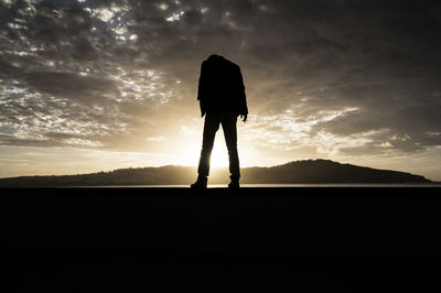 Silhouette person standing on field against sky during sunset