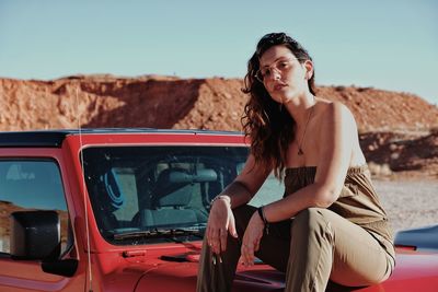 Portrait of beautiful woman in car against sky