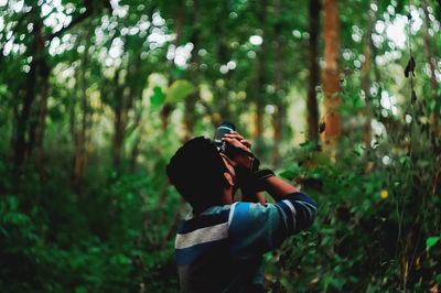 Man photographing against trees in forest