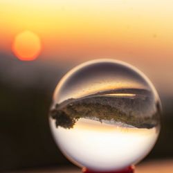 Close-up of crystal ball against sky during sunset