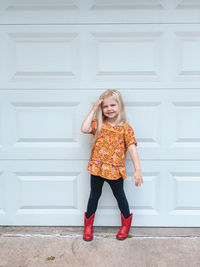 Portrait of smiling girl standing against wall