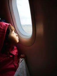Rear view of boy looking through airplane window