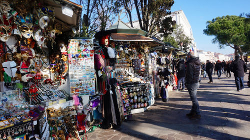 Masks hanging at street market with people walking