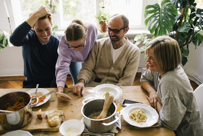 Girl sharing smart phone with family at dining table