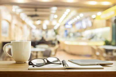 Close-up of coffee cup with diary and eyeglasses on table in office