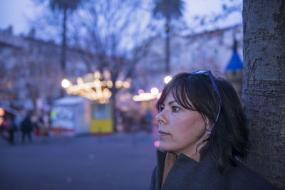 Thoughtful woman looking away in city at dusk